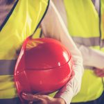 Two young workers hugging helmets