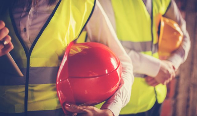 Two young workers hugging helmets