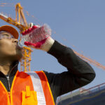 worker man  as he drinks from a plastic water bottle